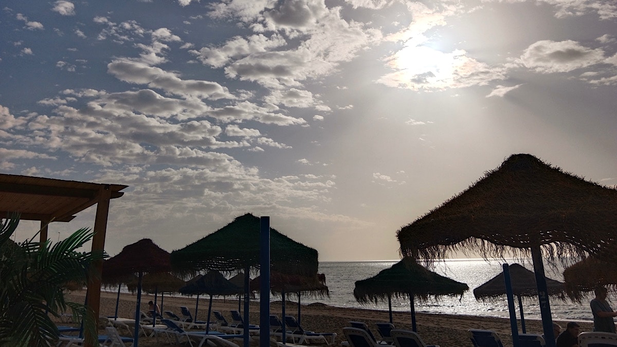 strand-ligbedden-parasols-ondergaande-zon-andalusie